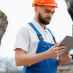 Bukósisakos dolgozó tabletet használ egy nagy építkezésen digitális adatrétegek megjelenítésével.