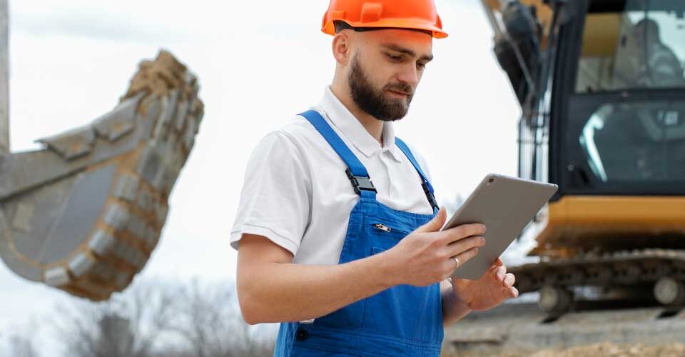 Bukósisakos dolgozó tabletet használ egy nagy építkezésen digitális adatrétegek megjelenítésével.